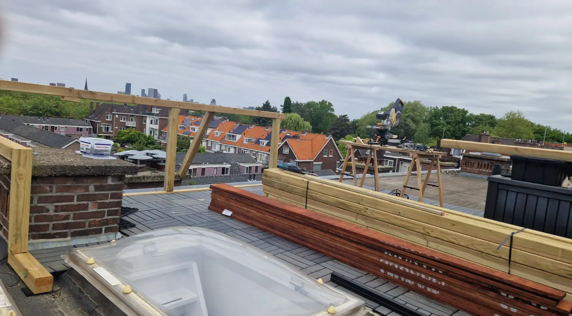 Dakterras in aanbouw met houten balustrade en zicht over de stad