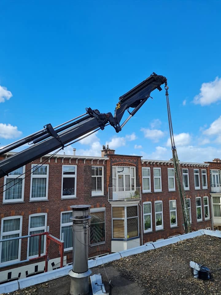 Kraan hijst bouwmateriaal tijdens een dakrenovatie in Den Haag